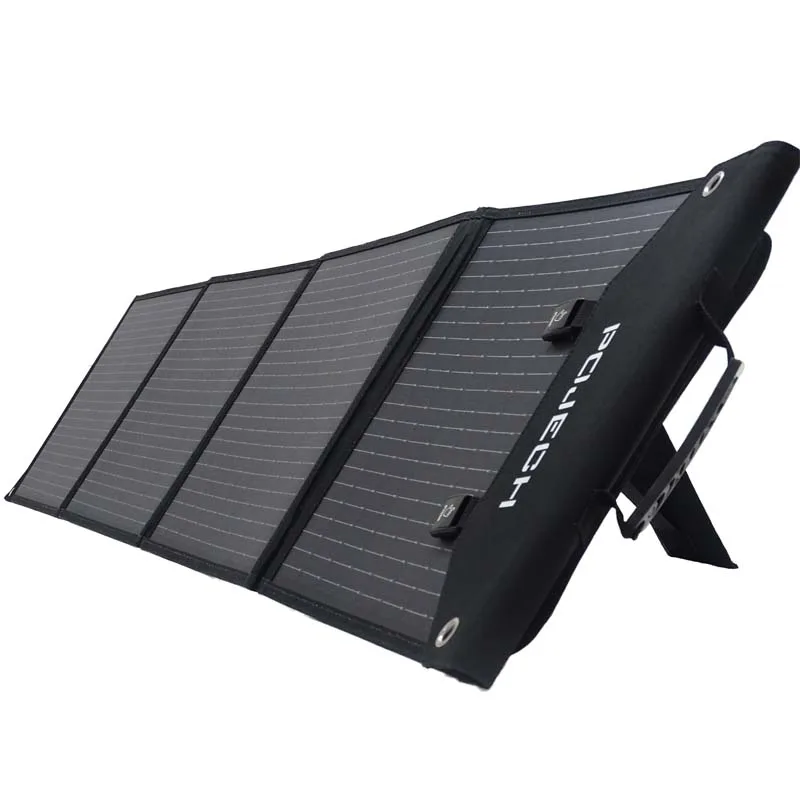 Foldable 100W solar panel fully deployed on grass with USB and MC4 outputs visible