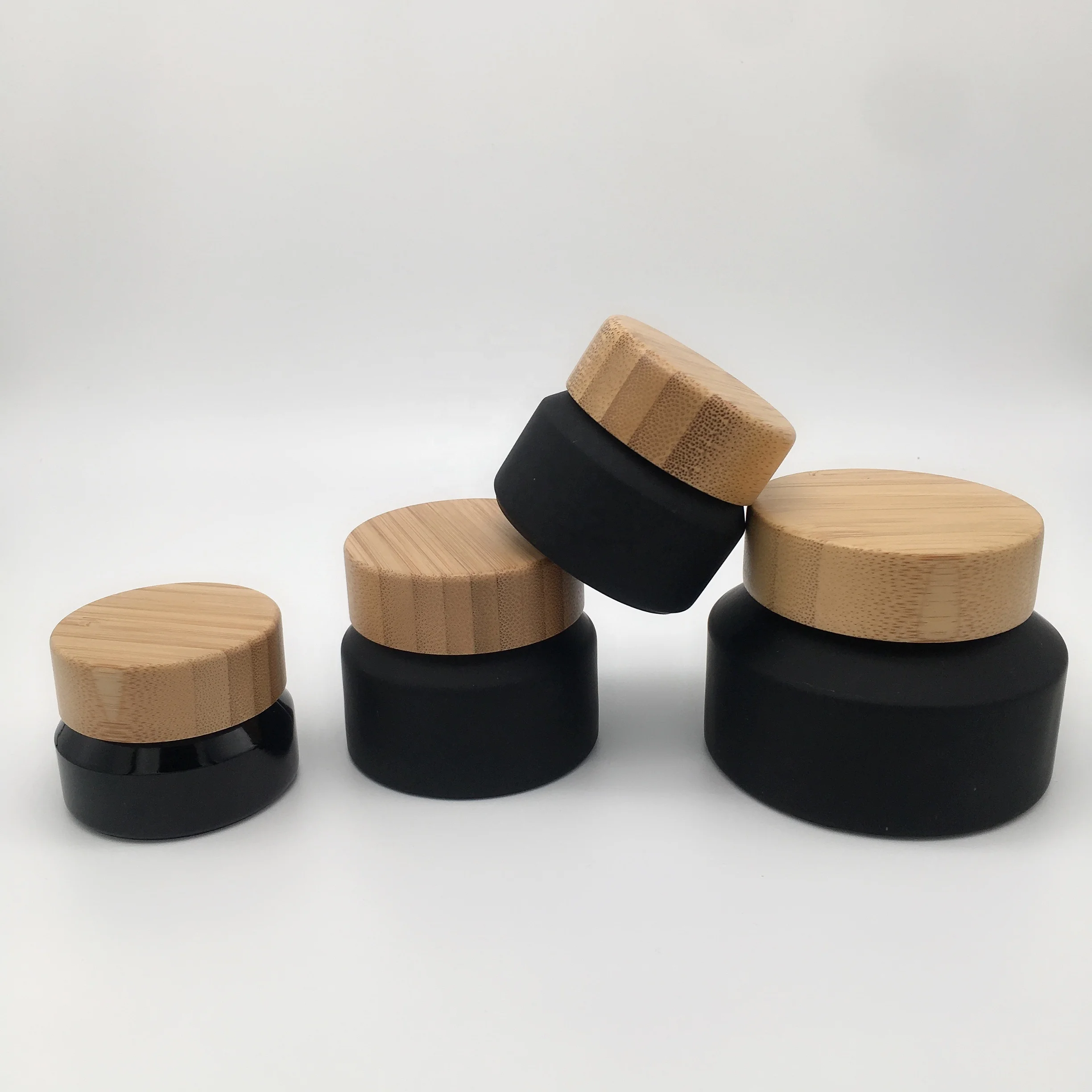 Factory hot sell cosmetic packaging frosted black glass bottle and jar with bamboo lid
