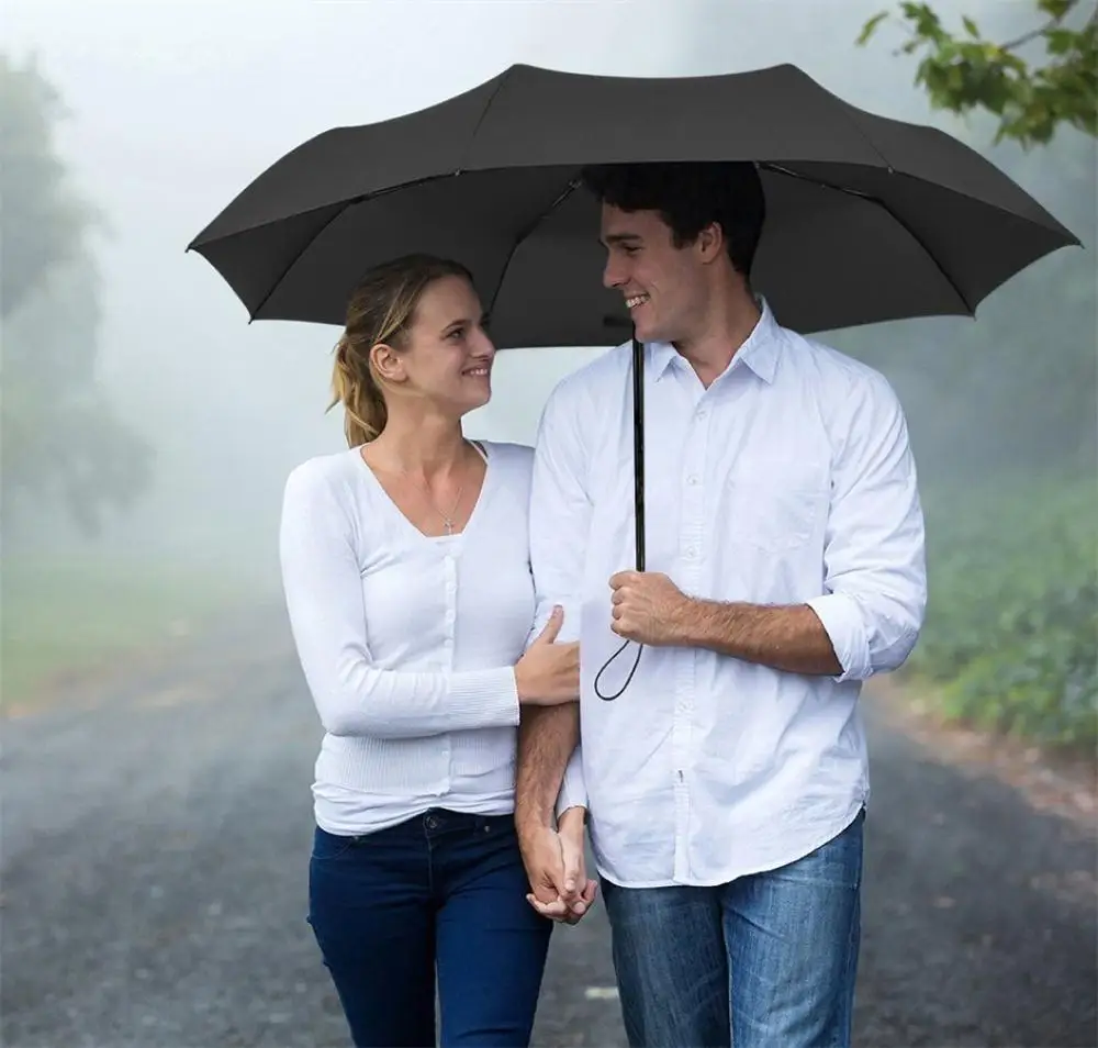 Мужчина держит зонт над женщиной