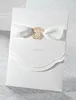 Glamorous & pure white wedding invitations with golden embossed pattern & white ribbons