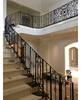 Site installing interior wrought iron stair railings with wood handrail on top