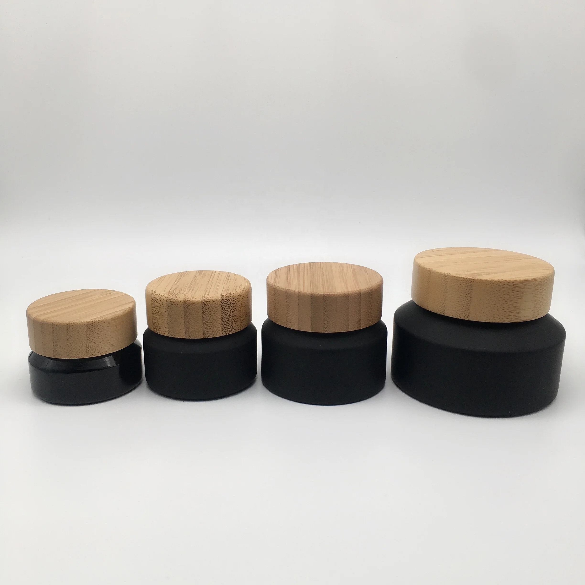 Factory hot sell cosmetic packaging frosted black glass bottle and jar with bamboo lid
